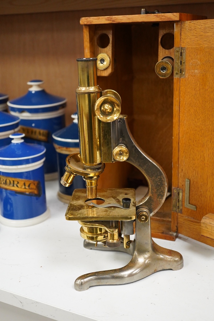 An early 20th century oak cased brass ‘Kima’ microscope by W. Watson & Sons Ltd. London, with engraved serial number under the maker’s name; 53622, with two alternative lenses in fitted compartments, microscope approxima